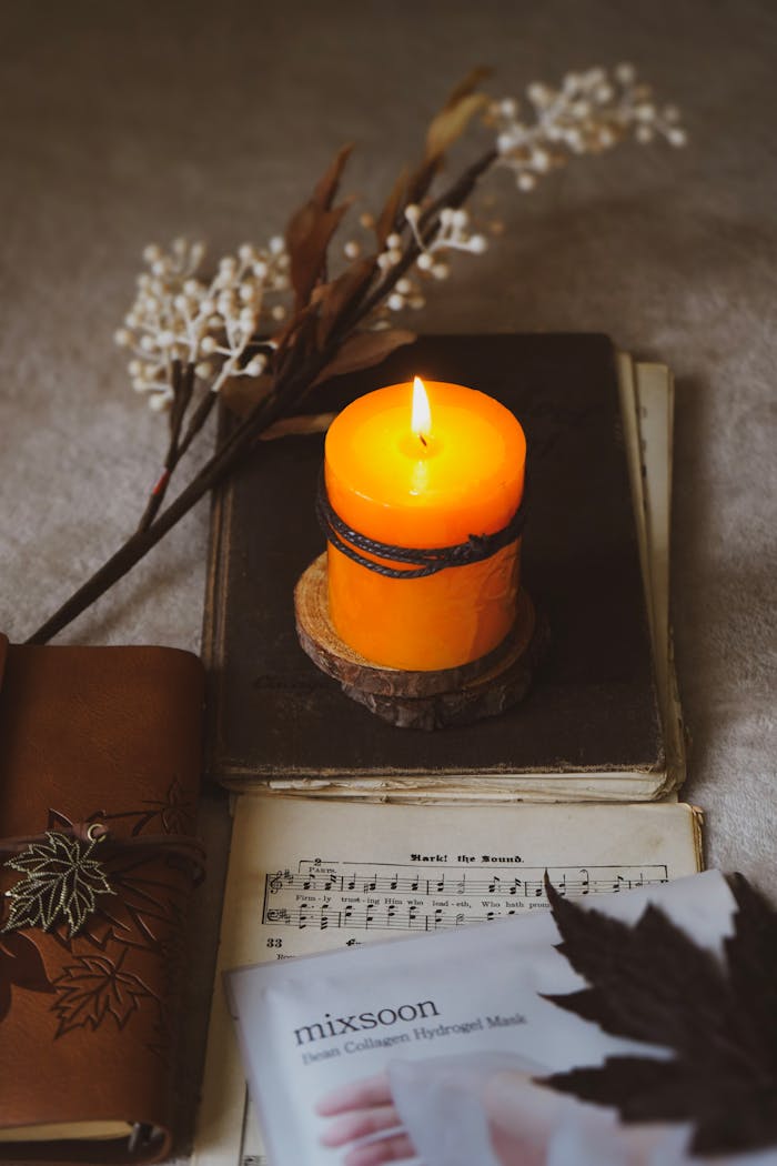 Warm autumn-themed still life with a glowing candle and vintage books.